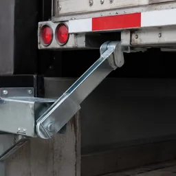Hook-style vehicle restraint engaged with trailer