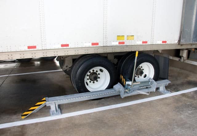 High-visibility wheel chock placed behind a trailer wheel as a backup vehicle restraint